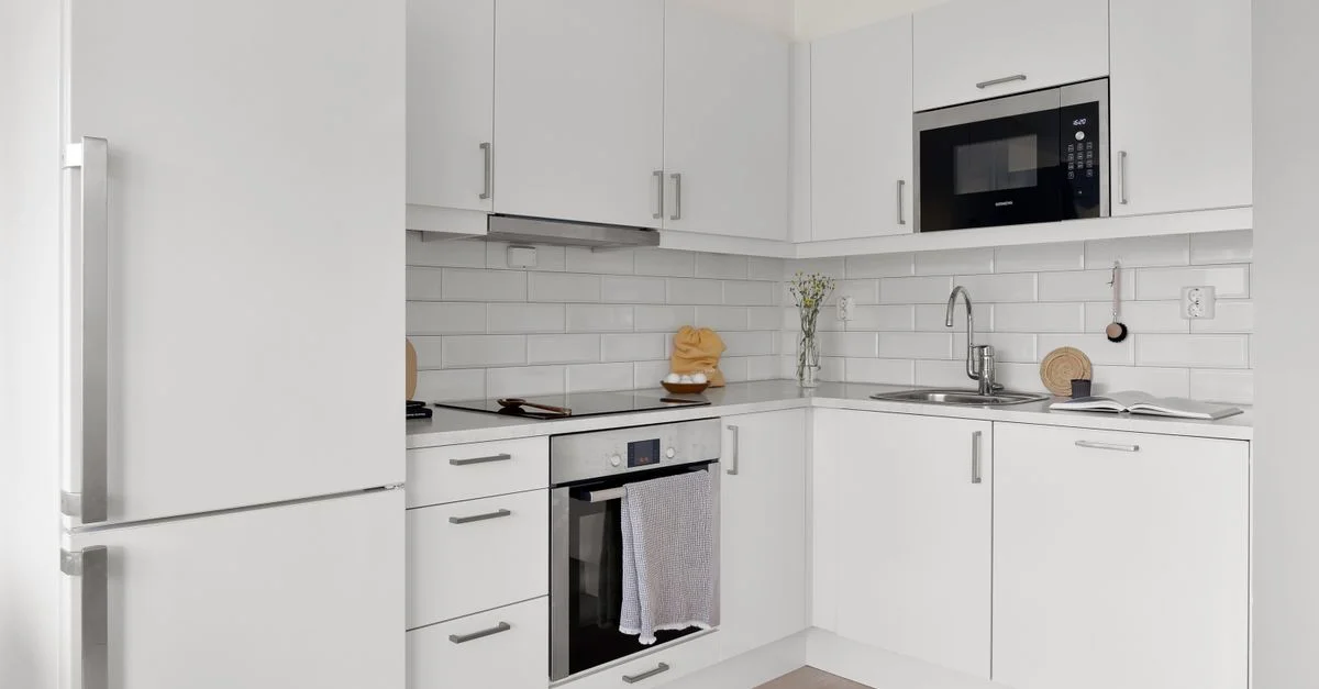 Cuisine blanche élégante avec des appareils modernes et une décoration minimaliste, parfaite pour l'élégance.