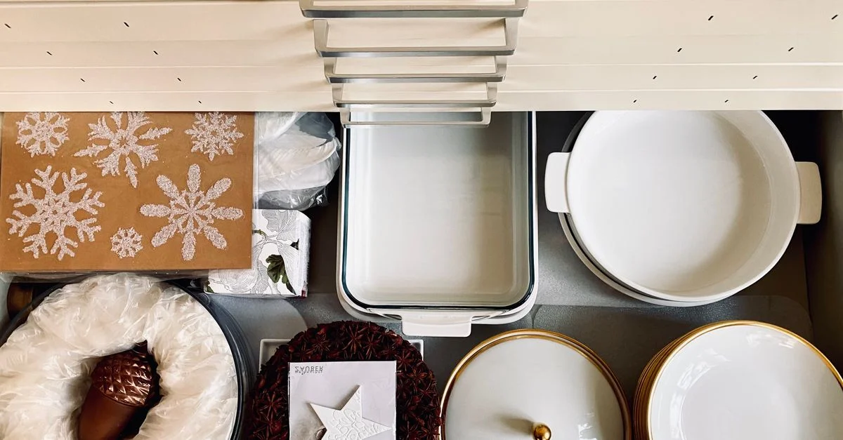 Vue de dessus d'un tiroir de cuisine organisé avec de la vaisselle et des décorations de fête, créant une présentation soignée et festive.