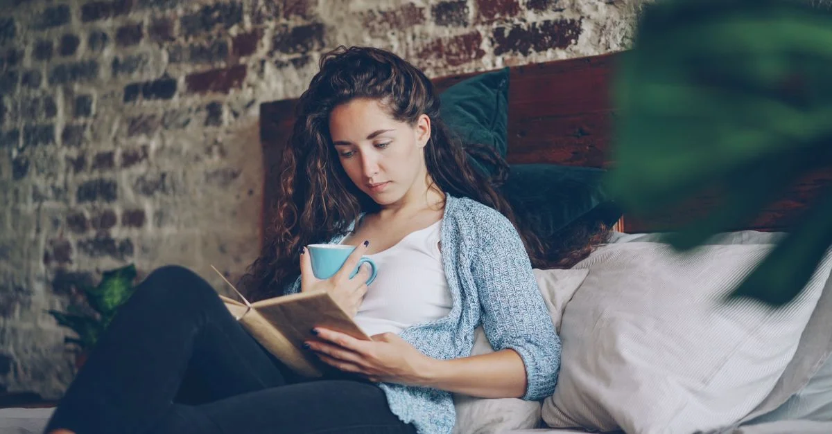 Femme profitant d'un moment de lecture confortable avec du café à l'intérieur. Atmosphère détendue et sereine.